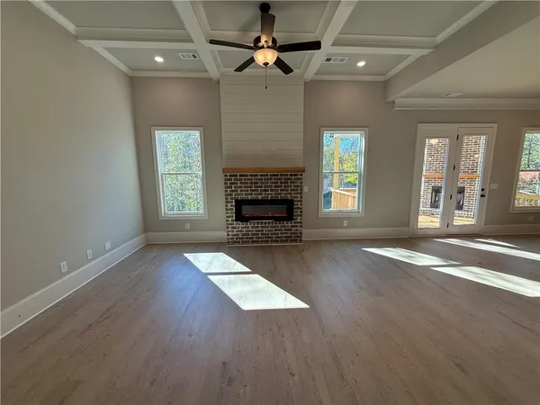 an empty room with windows fireplace and wooden floor