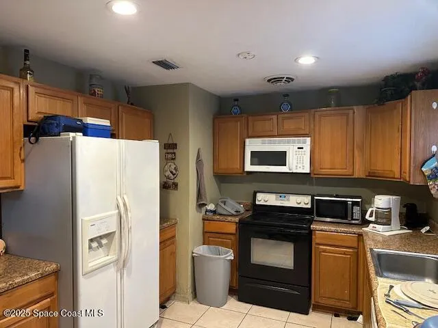 a kitchen with stainless steel appliances granite countertop a refrigerator a stove and a sink