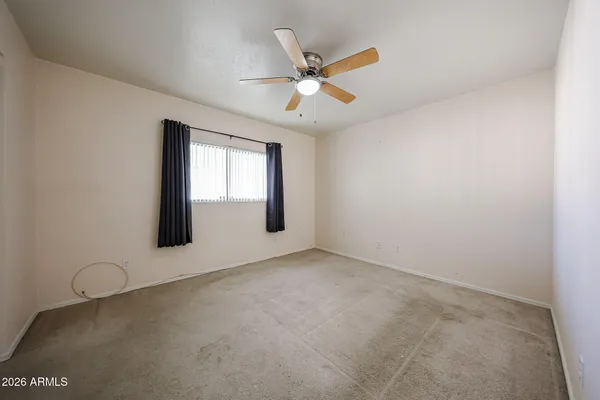 an empty room with windows and fan