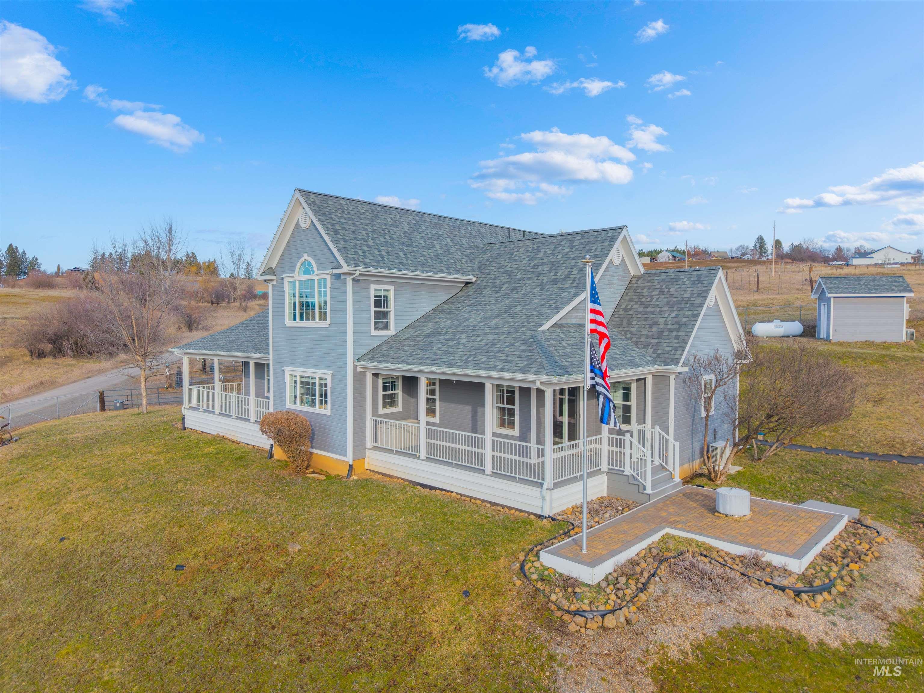 Back of house with a shingled roof, covered porch, and a yard