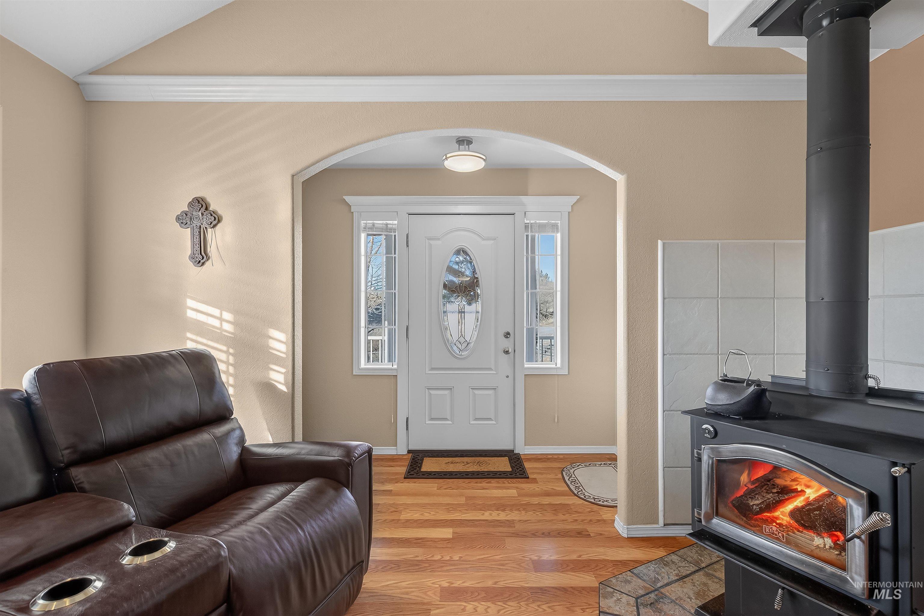 108 Tweedy Lane Kooskia, ID 83539 - Photo 20 of 48 Entryway featuring a wood stove, light wood-type flooring, ornamental molding, and arched walkways