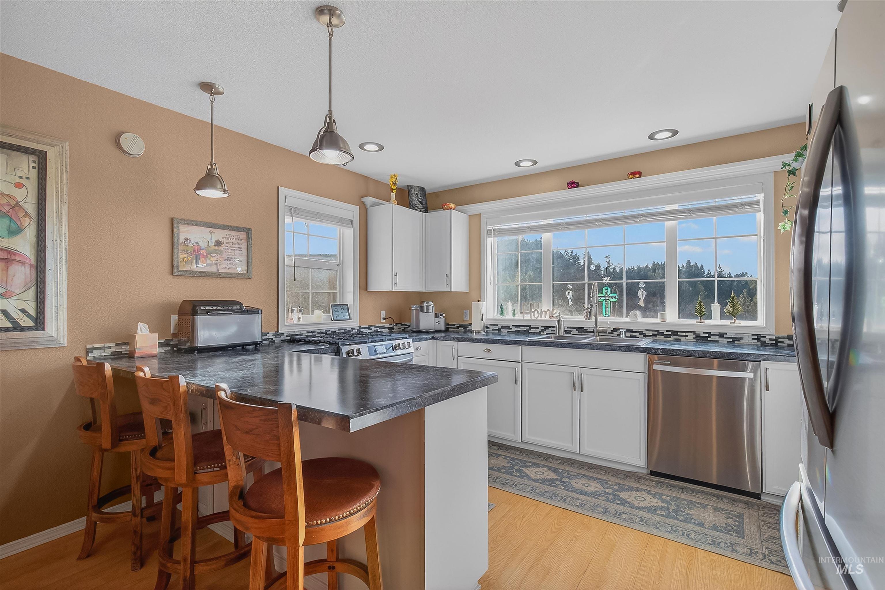 108 Tweedy Lane Kooskia, ID 83539 - Photo 24 of 48 Kitchen featuring a peninsula, appliances with stainless steel finishes, a kitchen breakfast bar, dark countertops, and light wood-style flooring