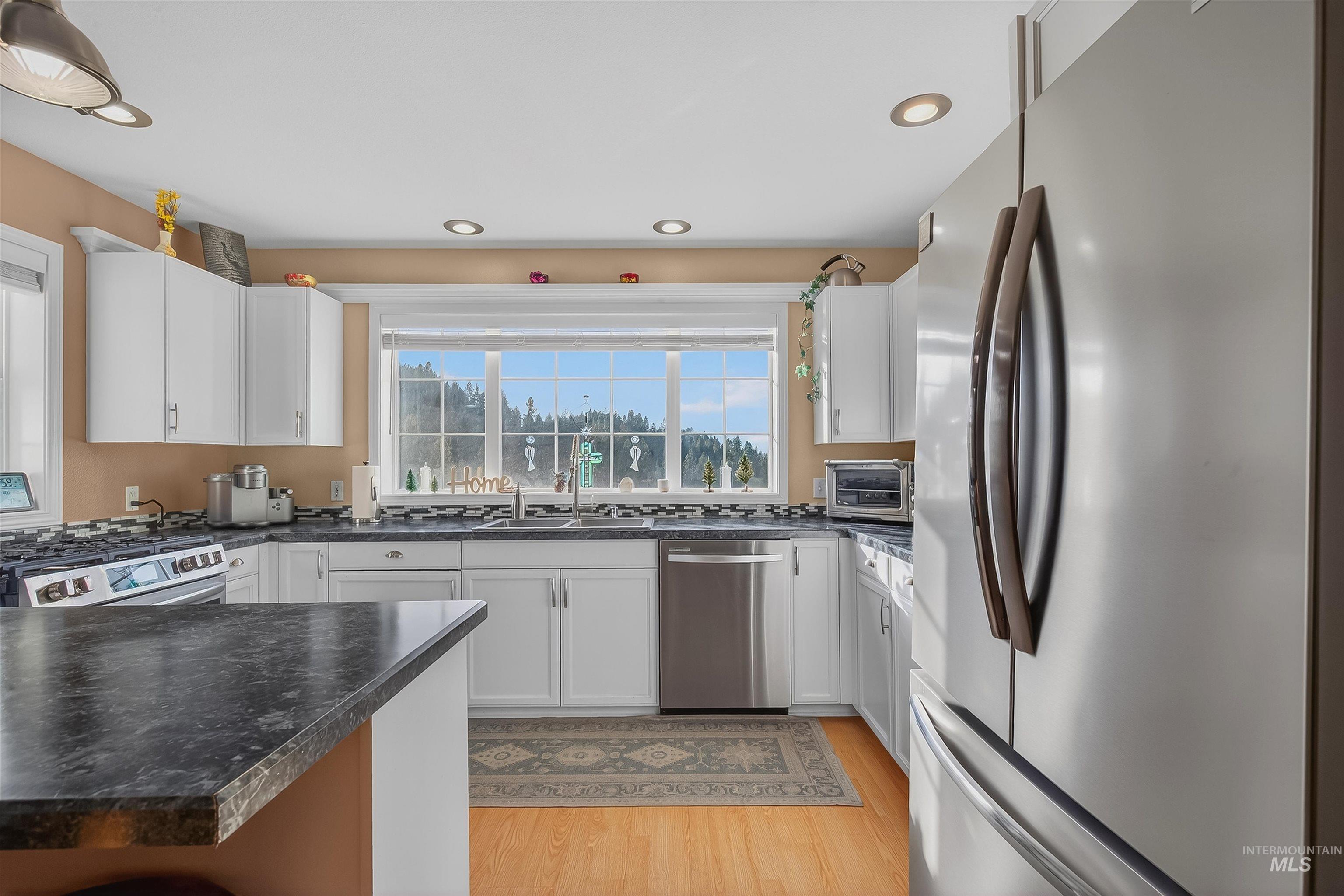 108 Tweedy Lane Kooskia, ID 83539 - Photo 25 of 48 Kitchen featuring stainless steel appliances, white cabinetry, light wood finished floors, recessed lighting, and a peninsula