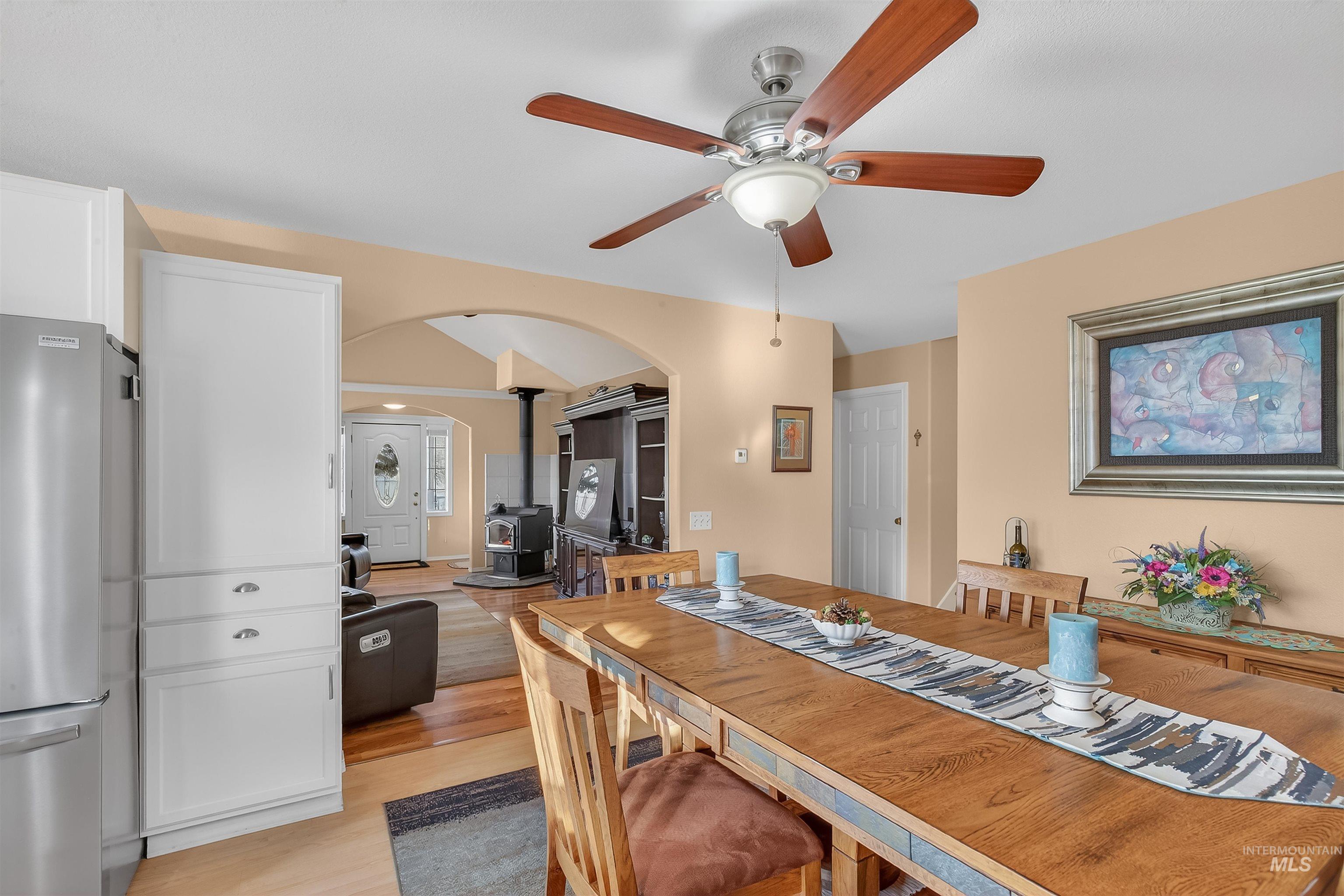 108 Tweedy Lane Kooskia, ID 83539 - Photo 27 of 48 Dining space with light wood-style floors, ceiling fan, arched walkways, a wood stove, and lofted ceiling
