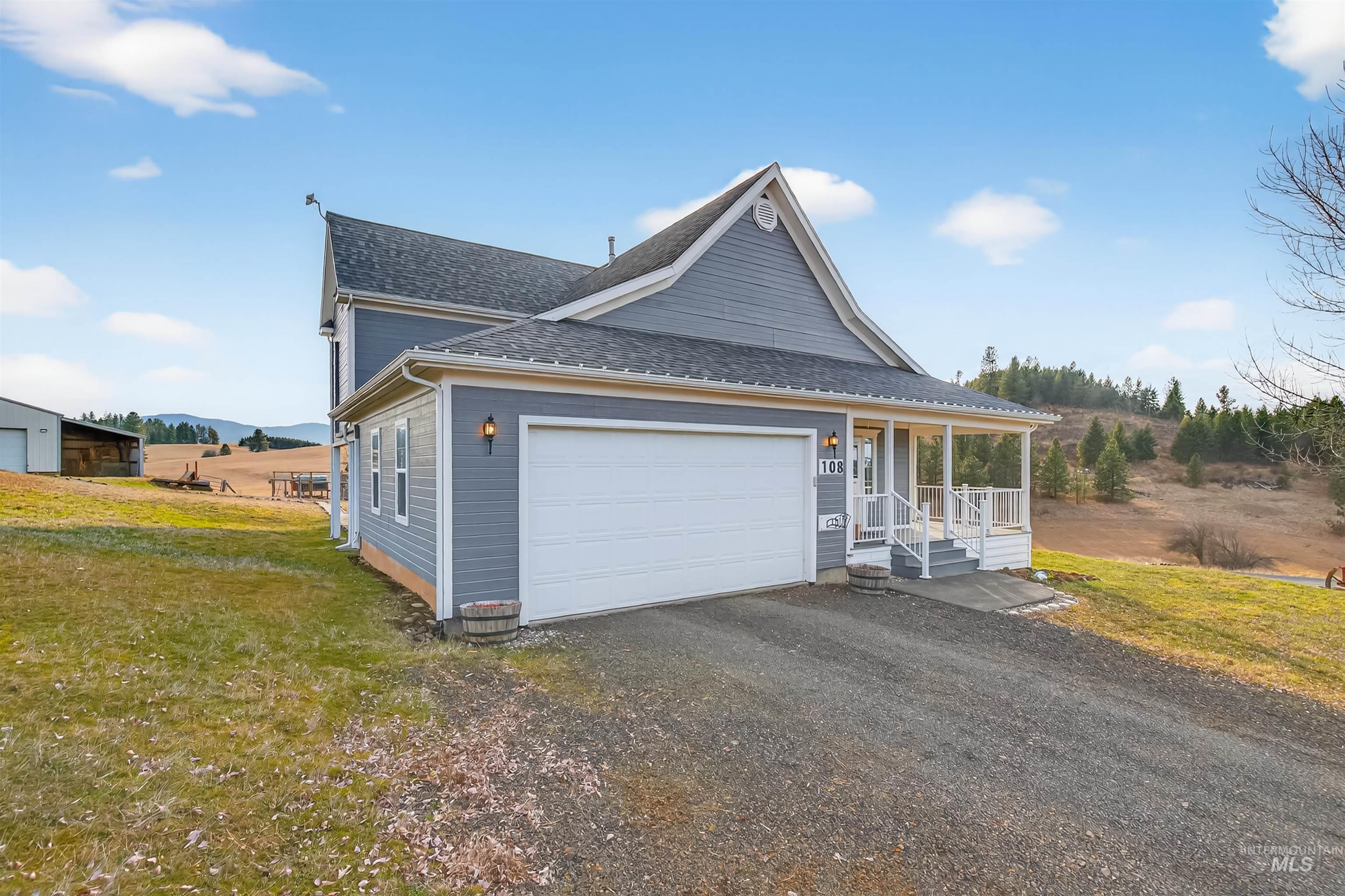 108 Tweedy Lane Kooskia, ID 83539 - Photo 4 of 48 View of front of property with covered porch, driveway, roof with shingles, a front yard, and an attached garage