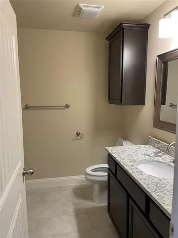 a bathroom with a granite countertop sink a toilet and mirror