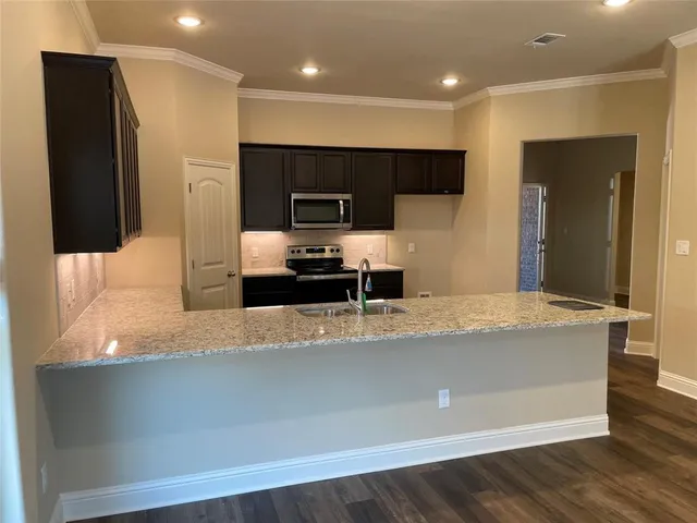 a large kitchen with stainless steel appliances a large counter top a stove and a refrigerator