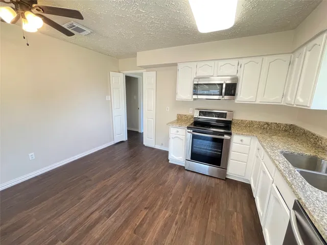 a kitchen with granite countertop a refrigerator and a stove top oven