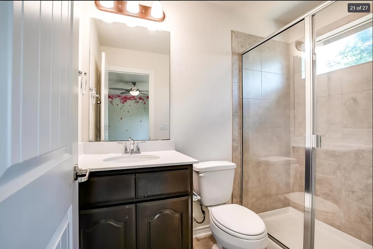14215 McCoy Loop Austin, TX 78717 - Photo 18 of 27 Bathroom featuring a dark wood-finish vanity with a white countertop and integrated sink, a frameless mirror, and overhead vanity lighting
