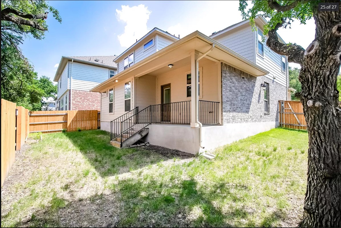 14215 McCoy Loop Austin, TX 78717 - Photo 26 of 27 Rear exterior featuring a covered patio with metal railings, a stone accent wall, and a wood privacy fence