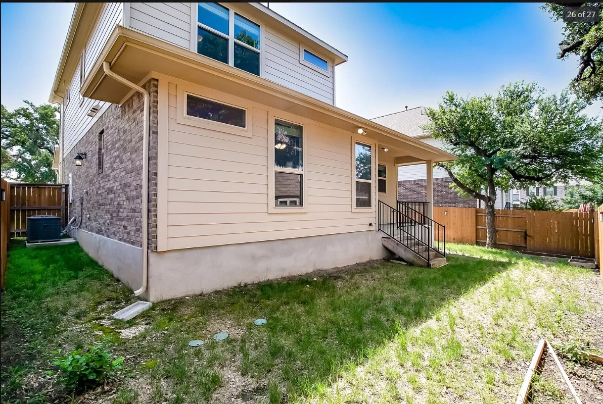 14215 McCoy Loop Austin, TX 78717 - Photo 27 of 27 Rear exterior featuring a covered patio with metal railings, brick and siding facade, and a wood privacy fence
