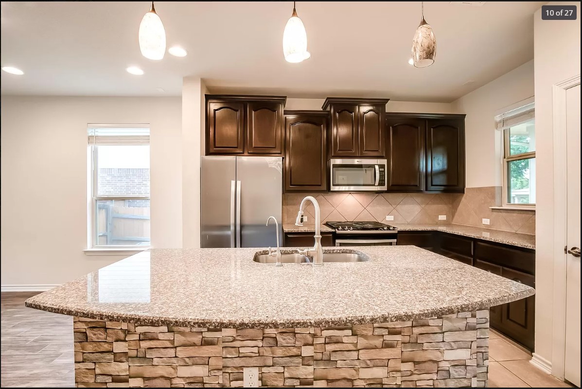 14215 McCoy Loop Austin, TX 78717 - Photo 7 of 27 Kitchen island with stone veneer base, integrated sink, and granite countertop