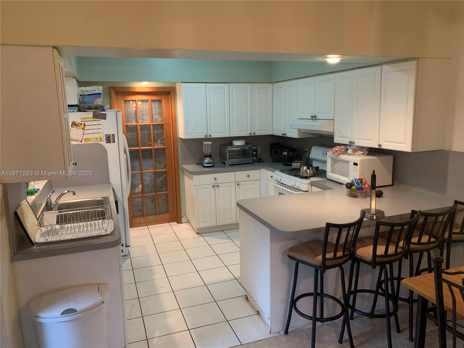 105 Southwest 22nd Road Miami, FL 33129 - Photo 7 of 26 a kitchen with a sink a stove and chairs
