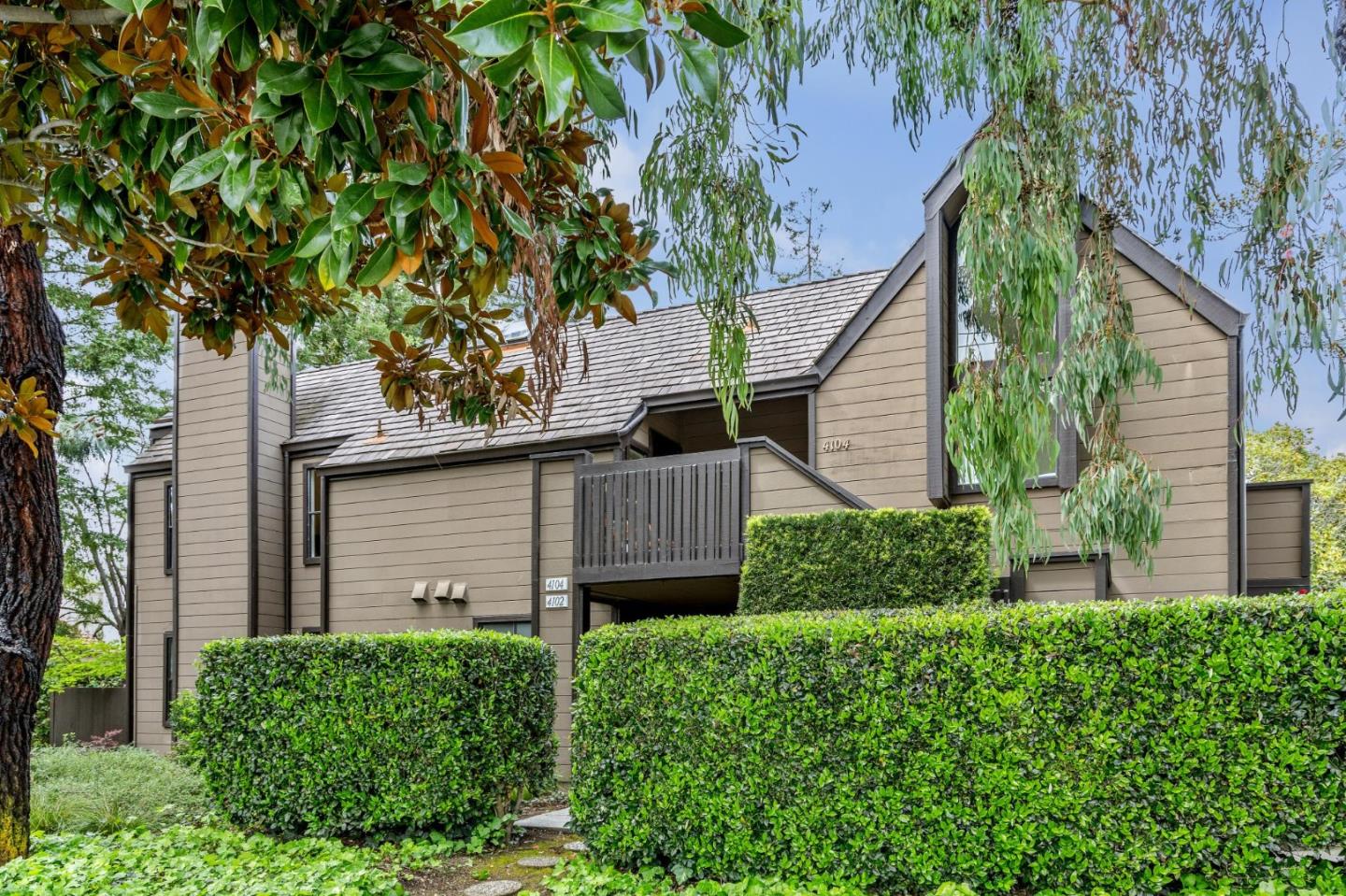 a view of a house with a small yard and a large tree