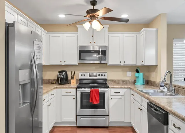 a kitchen with stainless steel appliances granite countertop a sink a stove a refrigerator cabinets and a refrigerator