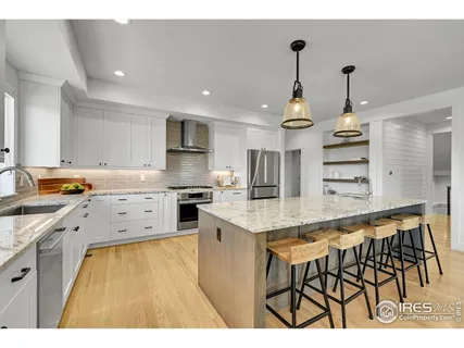 a open kitchen with kitchen island a stove a sink and white cabinets with wooden floor