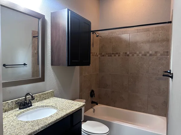 a bathroom with a granite countertop sink toilet and shower