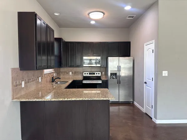 a kitchen with stainless steel appliances granite countertop a sink stove and refrigerator