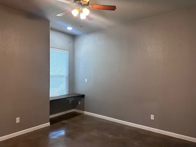 an empty room with windows and fan