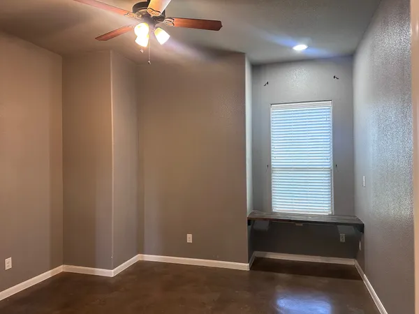 an empty room with windows and fan