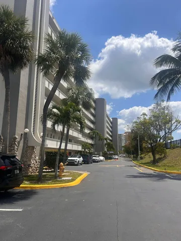 a view of swimming pool with a yard and palm trees