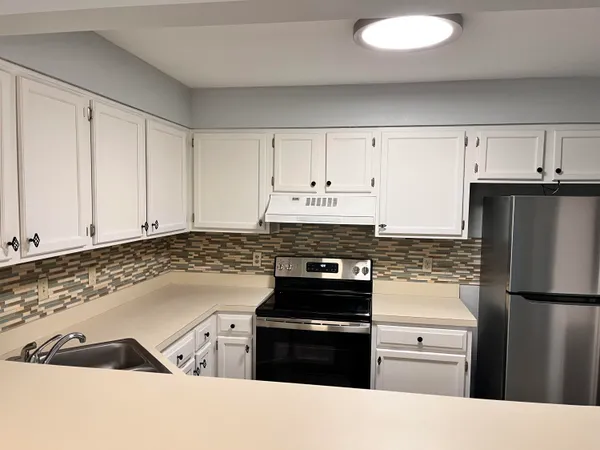 a kitchen with a refrigerator stove and white cabinets