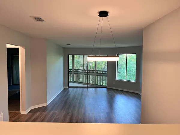 a view of an empty room with a window and wooden floor