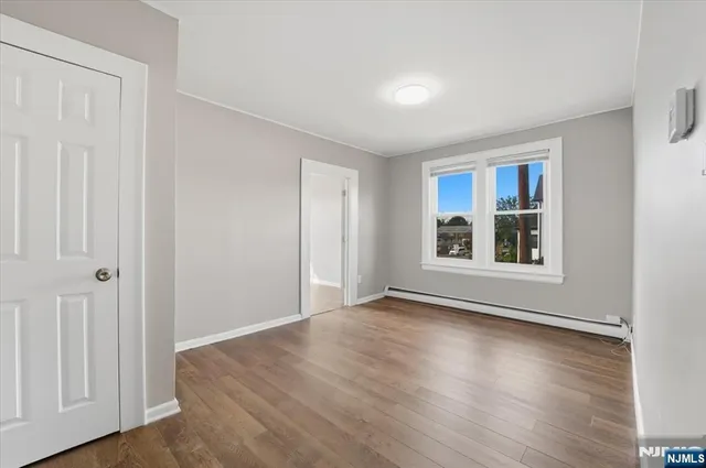 a view of an empty room with window and wooden floor