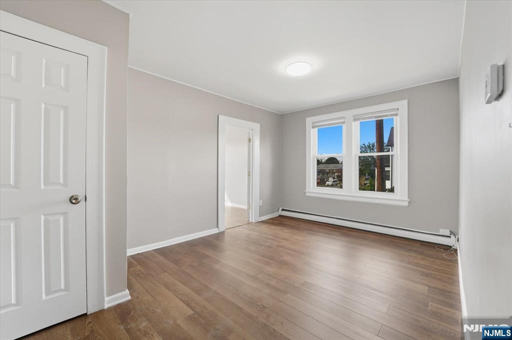 102 Exton Avenue North Arlington, NJ 07031 - Photo 6 of 18 a view of an empty room with window and wooden floor