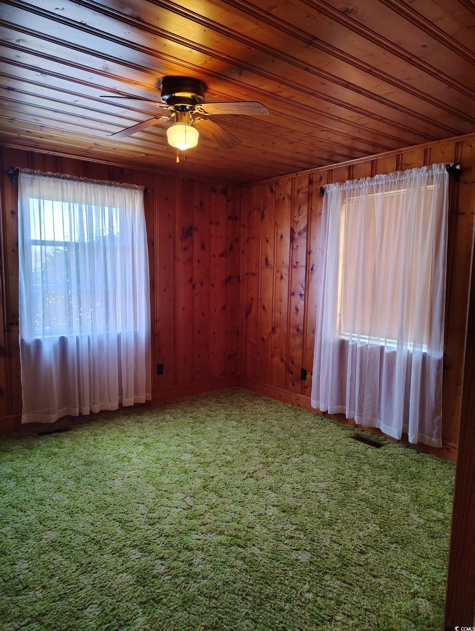 1375 Kenny Jordan Road Tabor City, NC 28463 - Photo 11 of 15 Carpeted spare room featuring a ceiling fan, wood ceiling, visible vents, and wood walls
