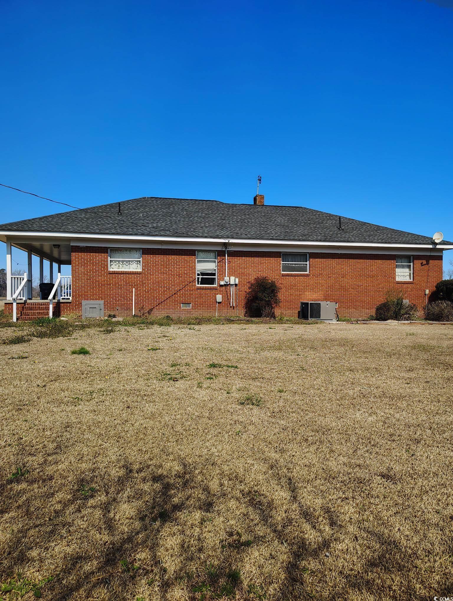 1375 Kenny Jordan Road Tabor City, NC 28463 - Photo 4 of 15 Exterior space featuring roof with shingles, brick siding, a lawn, and cooling unit