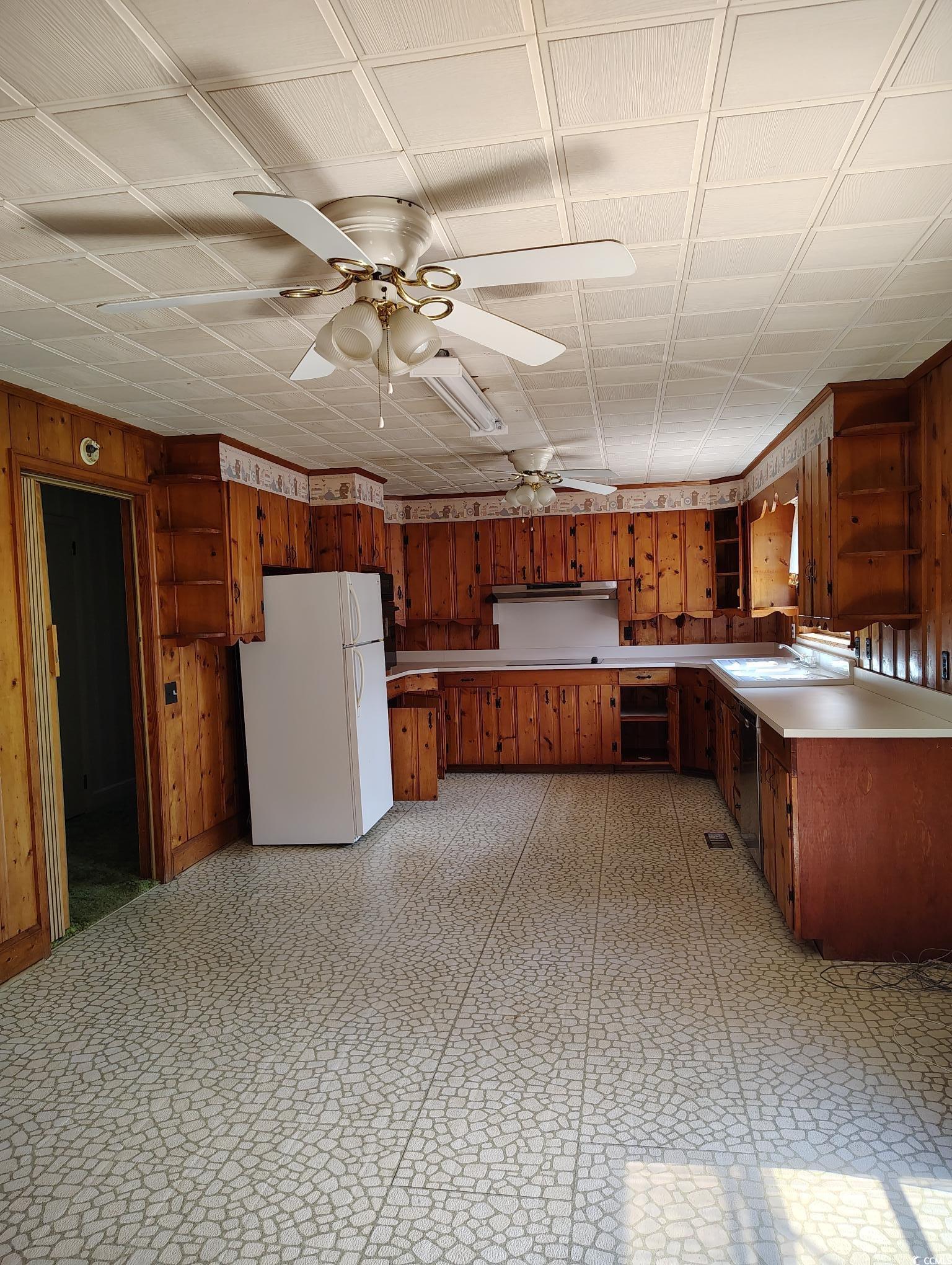 1375 Kenny Jordan Road Tabor City, NC 28463 - Photo 5 of 15 Kitchen featuring wood walls, brown cabinetry, light floors, and freestanding refrigerator