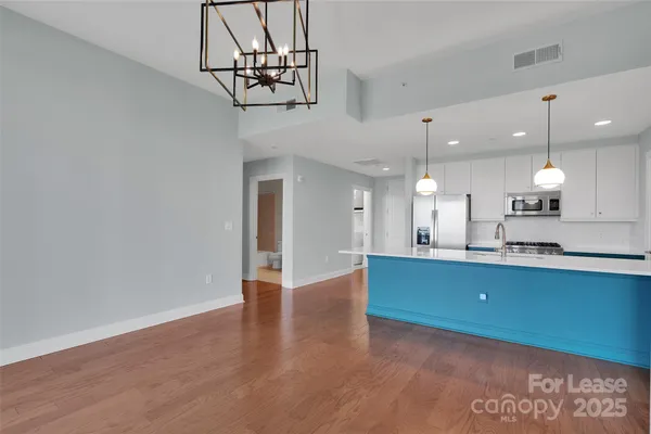 a kitchen with stainless steel appliances a refrigerator and a wooden floor