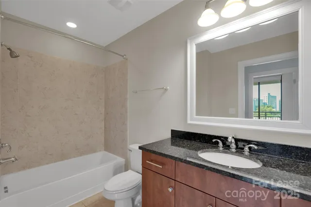 a bathroom with a granite countertop sink toilet mirror and bathtub