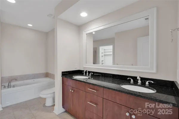 a bathroom with a granite countertop double vanity sink and a bathtub