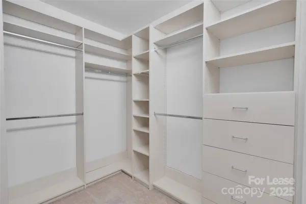 a view of walk in closet with empty racks