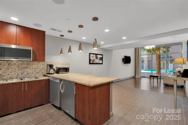 a kitchen with stainless steel appliances granite countertop a sink a stove top oven a dining table and chairs with wooden floor