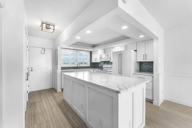 a large kitchen with a center island wooden floor and stainless steel appliances