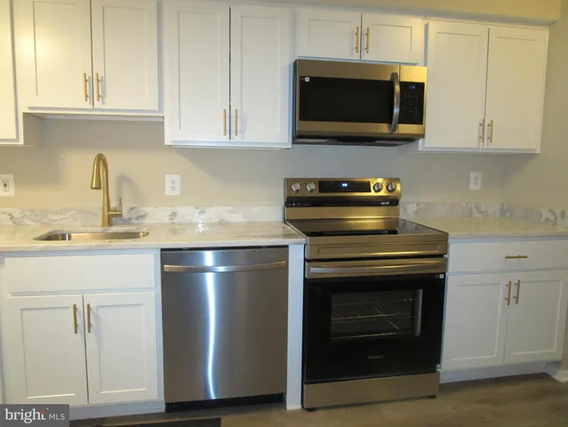 a kitchen with granite countertop white cabinets and stainless steel appliances