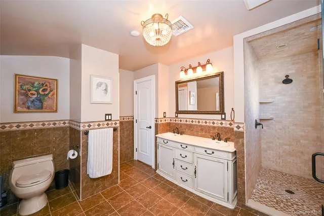 a spacious bathroom with a double vanity sink a toilet a mirror and shower