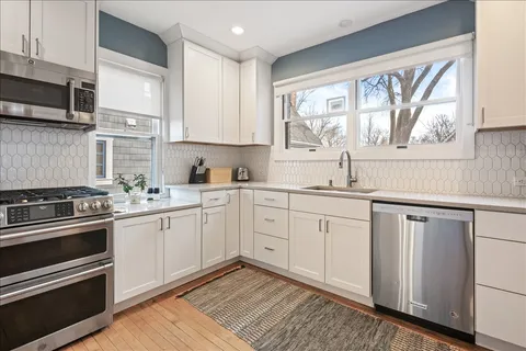 a kitchen with white cabinets appliances and a window
