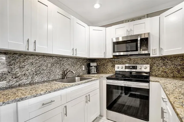 a kitchen with granite countertop white cabinets and appliances