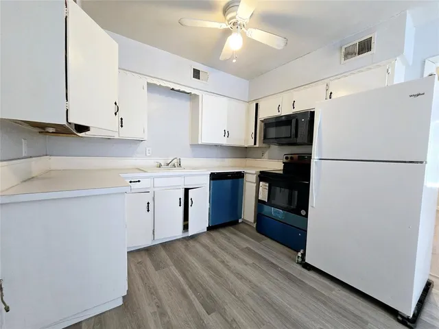 a kitchen with stainless steel appliances granite countertop a refrigerator a stove top oven a sink and dishwasher with wooden floor