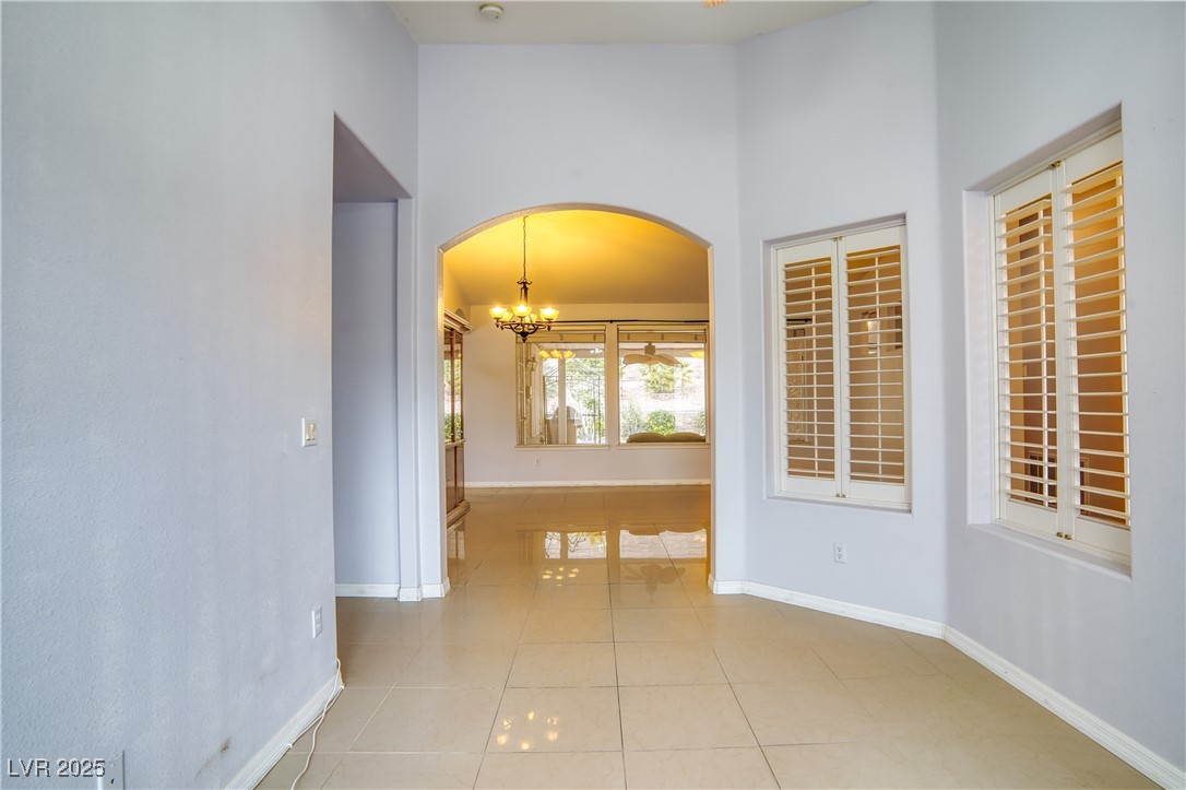 2383 Rainswept Avenue Henderson, NV 89052 - Photo 11 of 62 Hallway with light tile patterned floors, a chandelier, and arched walkways