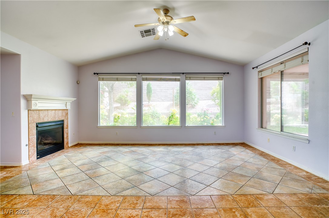 2383 Rainswept Avenue Henderson, NV 89052 - Photo 12 of 62 Unfurnished living room featuring plenty of natural light, a tile fireplace, vaulted ceiling, a ceiling fan, and light tile patterned floors