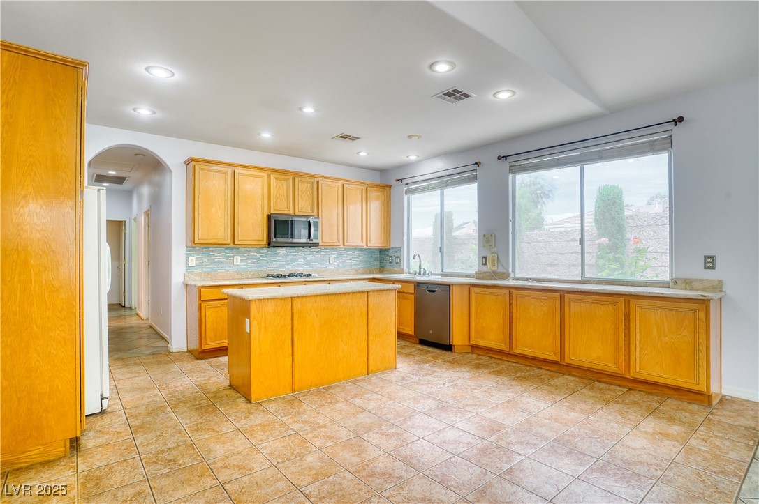 2383 Rainswept Avenue Henderson, NV 89052 - Photo 16 of 62 Kitchen featuring arched walkways, decorative backsplash, a kitchen island, stainless steel appliances, and recessed lighting