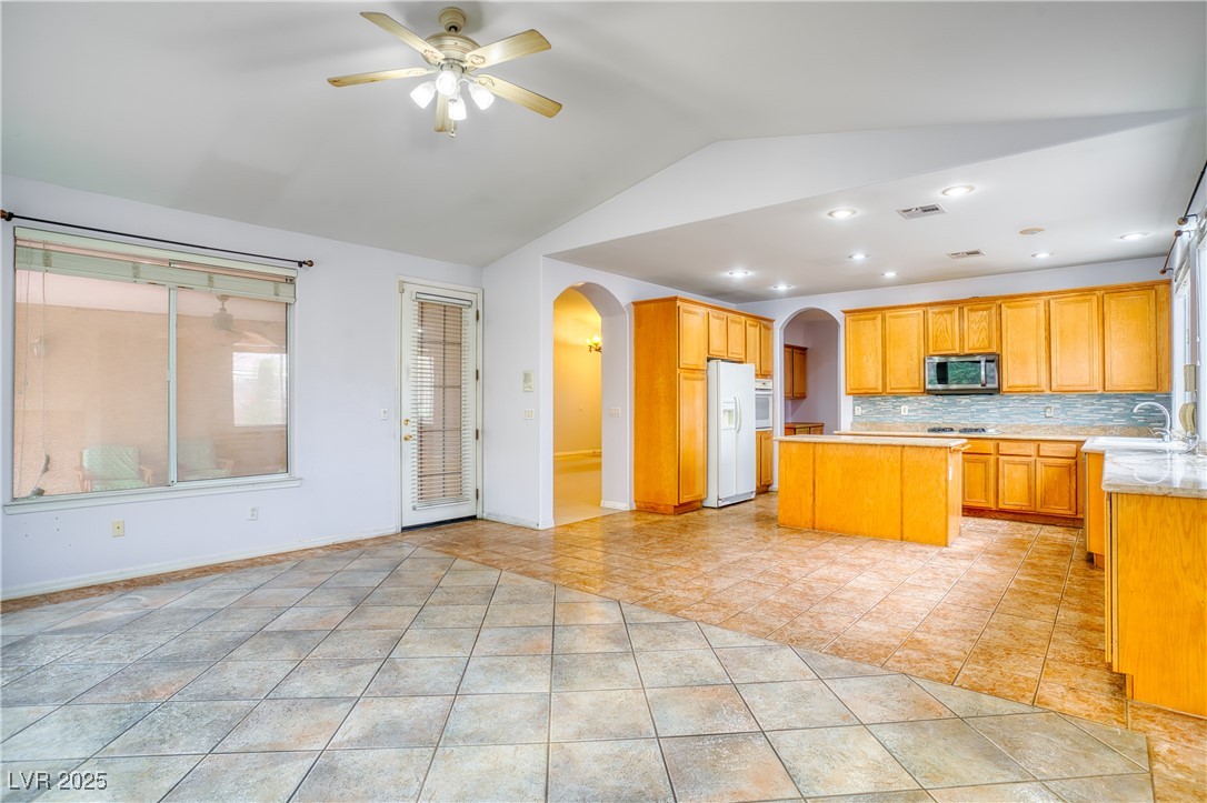 2383 Rainswept Avenue Henderson, NV 89052 - Photo 18 of 62 Kitchen with light countertops, tasteful backsplash, a kitchen island, white fridge with ice dispenser, and stainless steel microwave