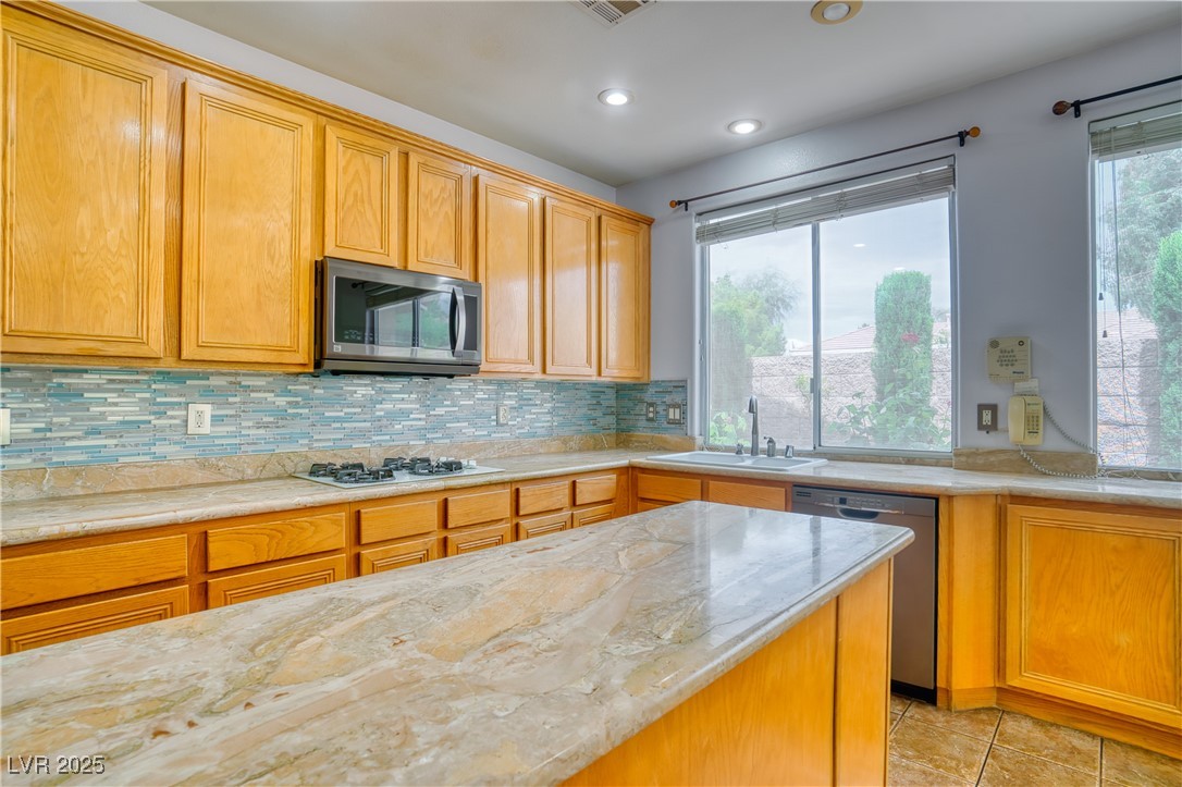 2383 Rainswept Avenue Henderson, NV 89052 - Photo 19 of 62 Kitchen with tasteful backsplash, light stone countertops, appliances with stainless steel finishes, recessed lighting, and light tile patterned flooring