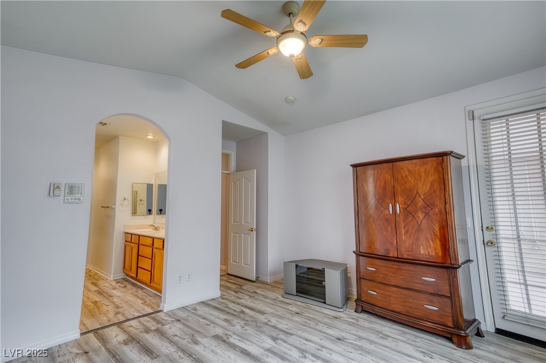 2383 Rainswept Avenue Henderson, NV 89052 - Photo 24 of 62 Unfurnished bedroom with lofted ceiling, connected bathroom, light wood-style floors, a ceiling fan, and arched walkways