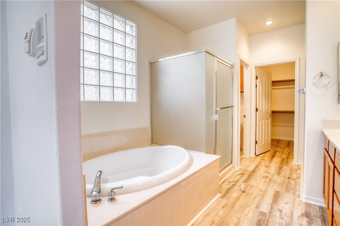2383 Rainswept Avenue Henderson, NV 89052 - Photo 25 of 62 Full bath featuring vanity, a walk in closet, a bath, a shower stall, and light wood finished floors
